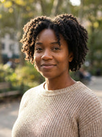 Woman with short curly hair wearing a beige sweater outdoors